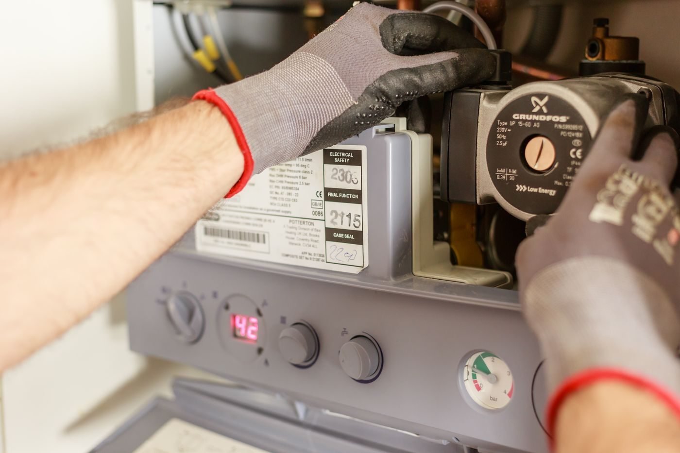 Técnico de luvas revisando os componentes internos de um aquecedor