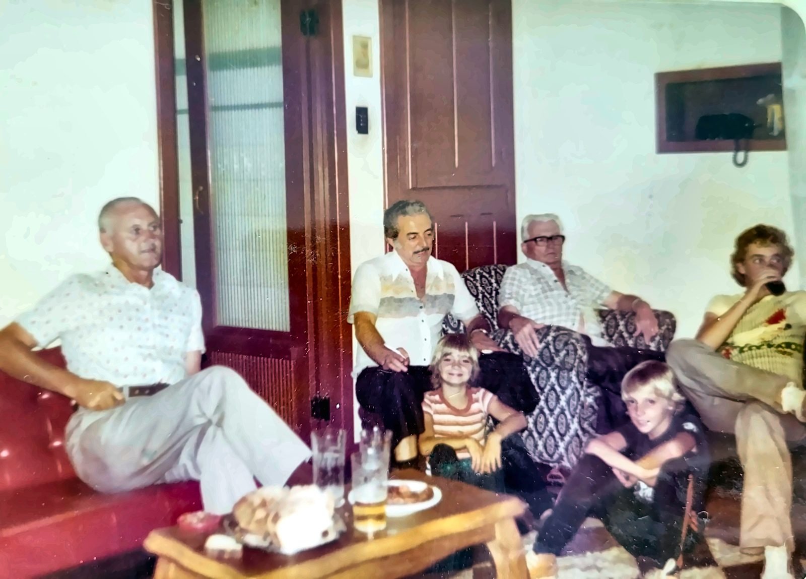 Reunião de família na sala, com adultos no sofá e crianças no chão